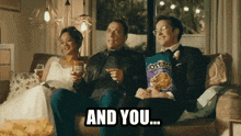 a couple sitting on a couch with a bag of tostitos chips