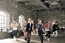 a group of people are dancing in a room with a brick wall