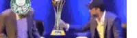 a blurred image of two men sitting in front of a trophy