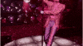 a man is standing on a pole in a club with a disco ball in the background