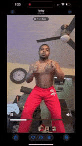 a phone screen shows a video of a shirtless man in red pants