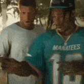 two men are standing next to each other looking at their cell phones .
