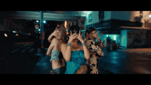 a woman in a blue dress is dancing in front of a building that says ' fuji ' on it