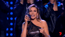 a woman in a black dress is holding a microphone in her hand while standing on a stage .