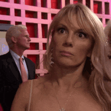a woman with blonde hair and a necklace is looking at the camera