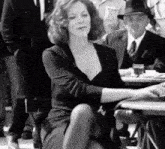 a woman is sitting at a table with a cigarette in her mouth .