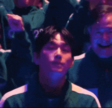 a group of people are sitting in a dark room and one of them has the number 100 on his jacket .