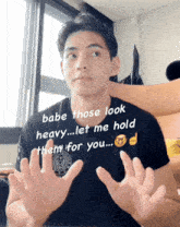 a man in a black shirt with the words babe those look heavy let me hold them for you