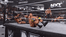 wrestlers in a ring with the word nxt on the wall