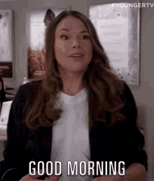 a woman in a white shirt and black jacket is saying good morning .