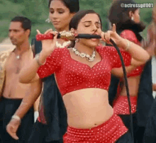a woman in a red crop top is singing into a microphone while dancing .