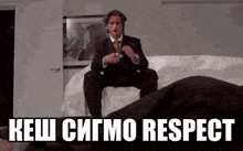 a man in a suit and tie is sitting on a bed with the words kesh sigmo respect below him
