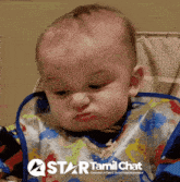 a baby wearing a bib with a star tamil chat logo on the bottom