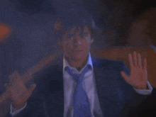 a man in a suit and tie is making a stop gesture