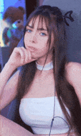 a woman with long hair and blue eyes is wearing a white top and a choker .