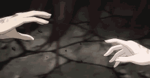 a couple of hands reaching out to each other on a dark surface .