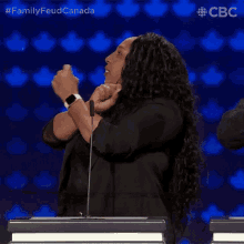 a woman giving a thumbs up in front of a microphone with the words family feud canada on the bottom