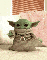 a baby yoda doll is sitting on a couch