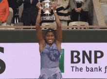 a woman is holding a trophy in front of an ad for bnp