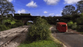a red bus is driving down a road near a train track