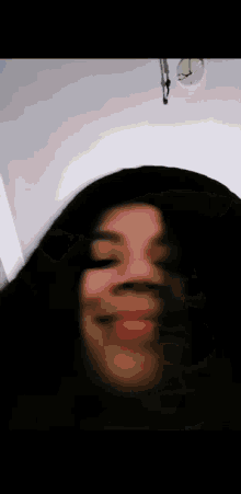 a woman with long black hair is making a funny face with her mouth open .