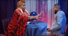 a man is sitting at a table with a fortune teller talking to him .