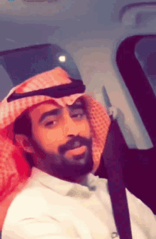 a man with a beard wearing a head scarf and a white shirt
