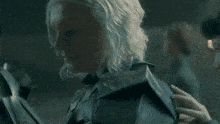 a woman with white hair is standing in a dark room