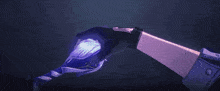 a person 's hand is holding a purple object in a dark room .