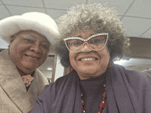 two women posing for a picture with one wearing a fur hat and glasses