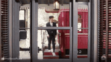 a man in a suit is walking through a doorway to a red bus .