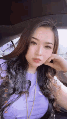 a woman is sitting in a car with her hand on her face .