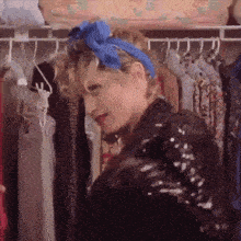 a woman wearing a blue headband is standing in a closet filled with clothes