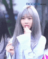 a girl with gray hair is making a heart shape with her fingers