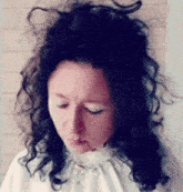 a woman with curly hair wearing a white shirt