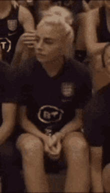 a woman in a purple shirt is sitting in a chair with her legs crossed .