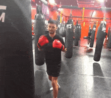 a man wearing red boxing gloves is in a gym with ufc bags