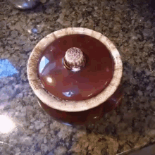 a red bowl with a wooden handle sits on a granite counter