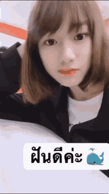 a girl is sitting at a table with a picture of a whale and the words " ฝัน ดี ค่ะ "