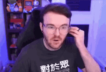a man wearing glasses and a t-shirt with chinese characters is sitting in a chair .