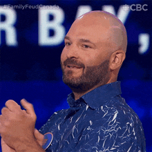 a bald man with a beard wearing a blue shirt is clapping