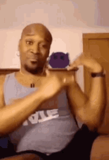 a bald man wearing a nike tank top is holding a stuffed animal