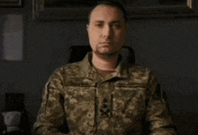 a man in a military uniform is sitting in a chair and looking at the camera