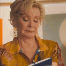 a woman wearing a yellow shirt is holding a book
