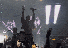 a man singing into a microphone in front of a crowd with a huge screen behind him that says ii