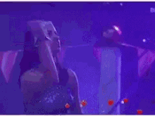 a woman in a purple dress is dancing in a dark room