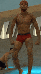 a shirtless man in red underwear is standing in front of a sign that says tommy hilfiger