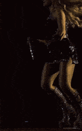a woman is kneeling on the floor on a stage wearing platform boots and a black dress .