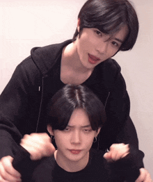 two young men are posing for a picture and one of them is wearing a black jacket