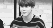 a black and white photo of a young boy wearing a striped sweater .